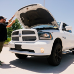 An inspector looking under the hood of a vehicle