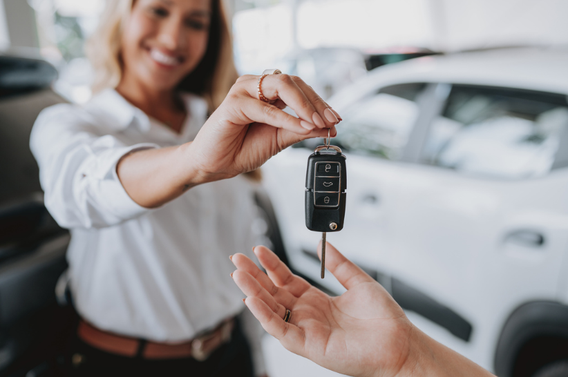 woman handing a car key into someone's hand.