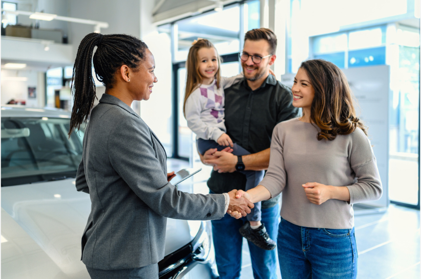 A family works with a car dealer to purchase a vehicle