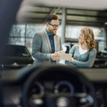 Car dealers talking outside a car.