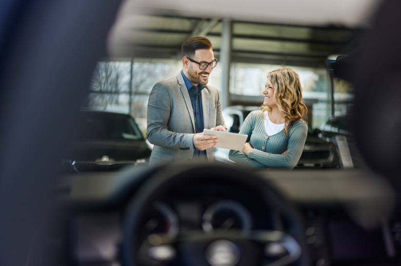 Car dealers talking outside a car.
