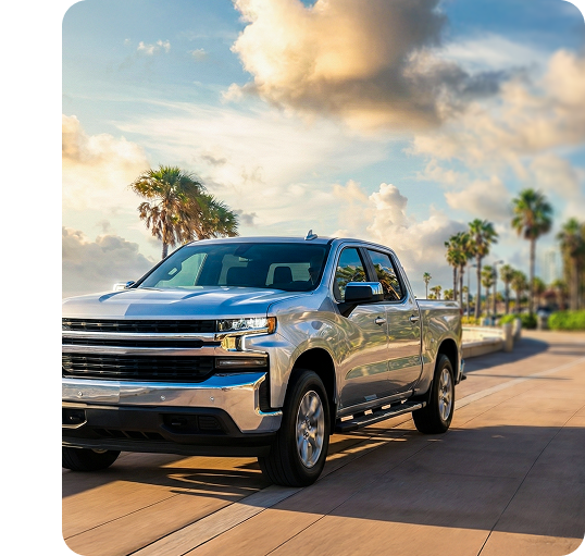 Silver Truck driving along a beach with palm trees in the background