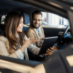 Woman and Man sitting inside a car looking at an IPAD.