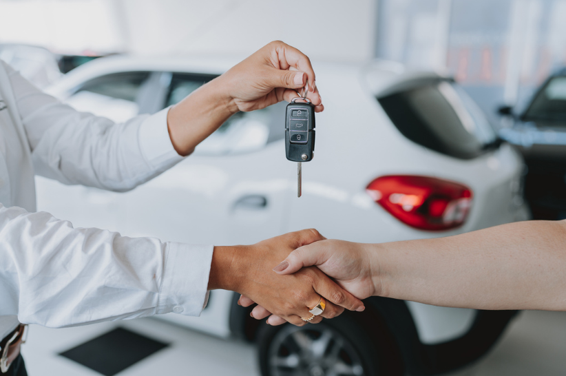 A man shaking hands with a woman and handing her car keys