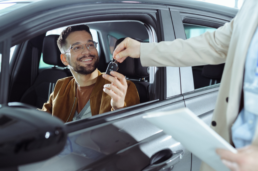 A man sitting in the front seat of a car grabbing keys.
